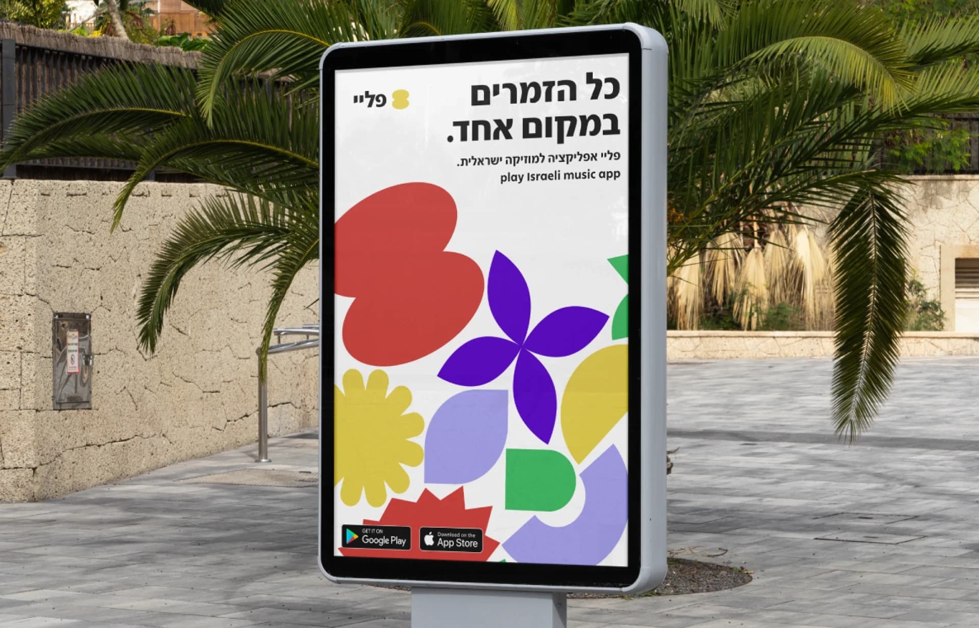 A freestanding street poster with the same Hebrew headline above a composition of colorful shapes.